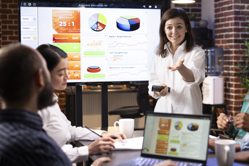 Business analyst presenting data dashboards and charts during a team meeting using business analytics software.